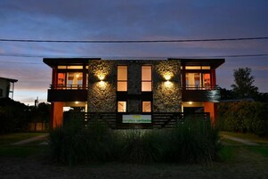 Un edificio moderno con fachada de piedra, dos balcones y un letrero que indica un negocio o servicio.