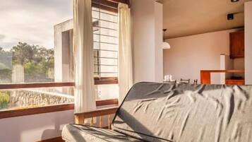 Una habitación con un sofá, una ventana con cortinas y vistas al exterior.