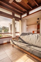 Una habitación con un sofá, una ventana con cortinas y vistas al exterior.