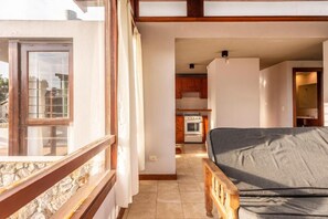 Un interior moderno con sofá, cocina y balcón con pared de piedra.