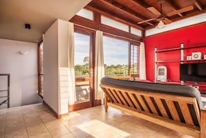 Una habitación con un banco de madera, una pared roja y vistas a través de un ventanal.