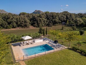 A swimming pool with lounge chairs and a covered seating area, surrounded by a fenced garden with trees and a view of distant hills. - Great garden, 2 bedrooms, ideal for couples (Pollensa / Pollença)