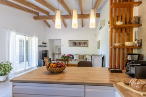 Una cucina con un piano di lavoro in legno, una ciotola di frutta, una macchina per il caffè e una pagnotta.