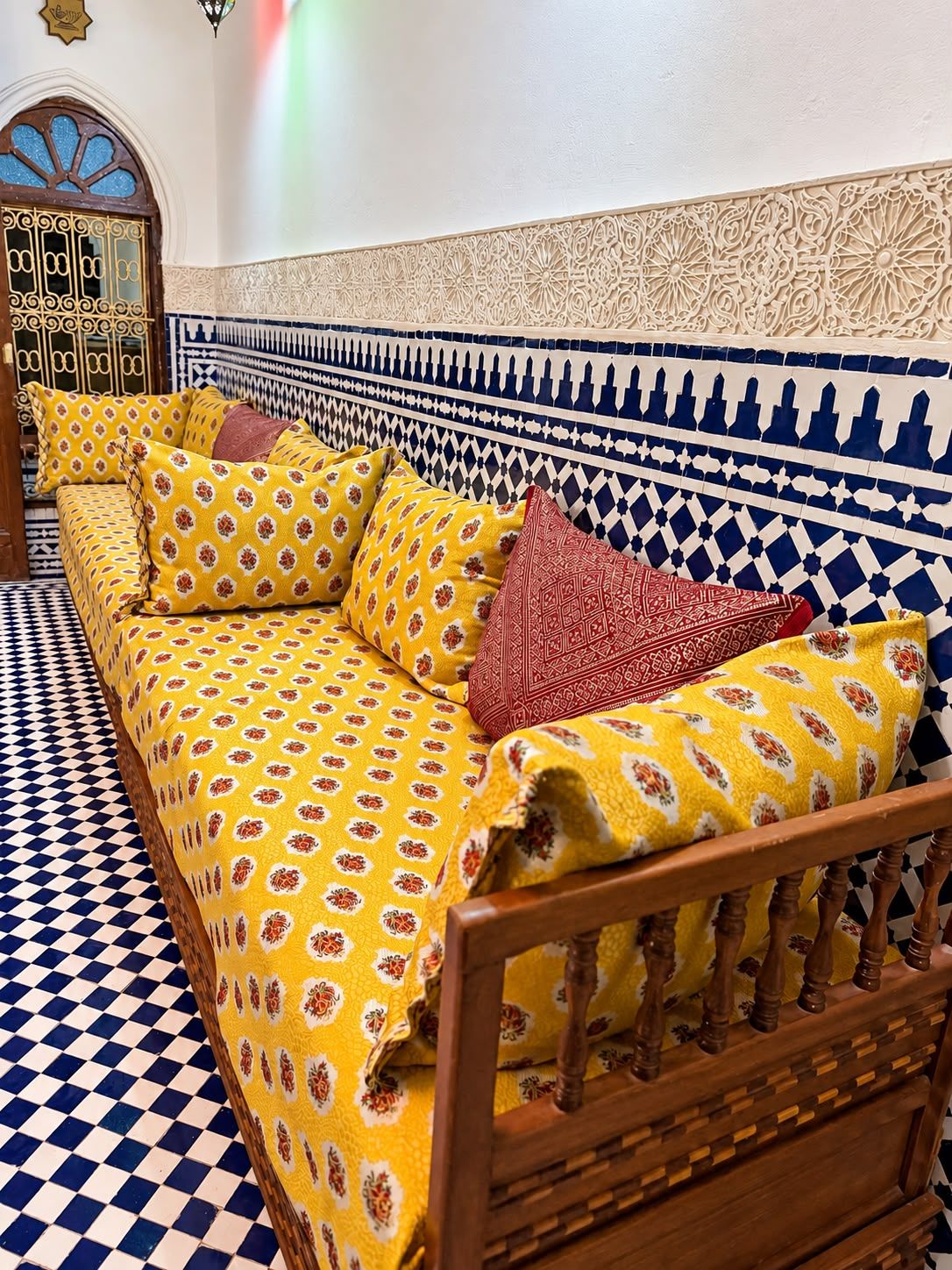 Quarto com um sofá estampado, chão xadrez e parede decorativa.