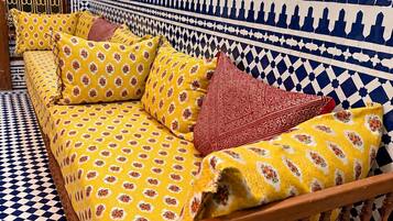 Quarto com um sofá estampado, chão xadrez e parede decorativa.