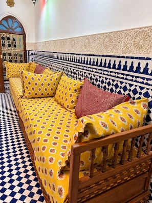 Una habitación con un sofá estampado, piso a cuadros y una pared decorativa.