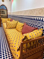 Quarto com um sofá estampado, chão xadrez e parede decorativa.