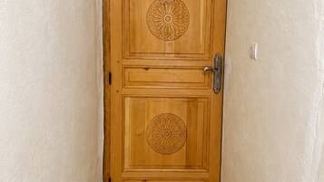 A wooden door with a number '5' and decorative patterns, a door handle, and a tiled floor.