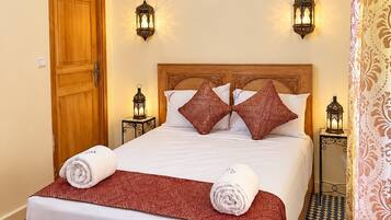 A hotel room with a wooden bed, patterned pillows, and a checkered floor.