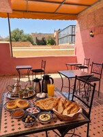 Área de refeições ao ar livre com mesa posta para o café da manhã, incluindo pão, ovos e bebidas.