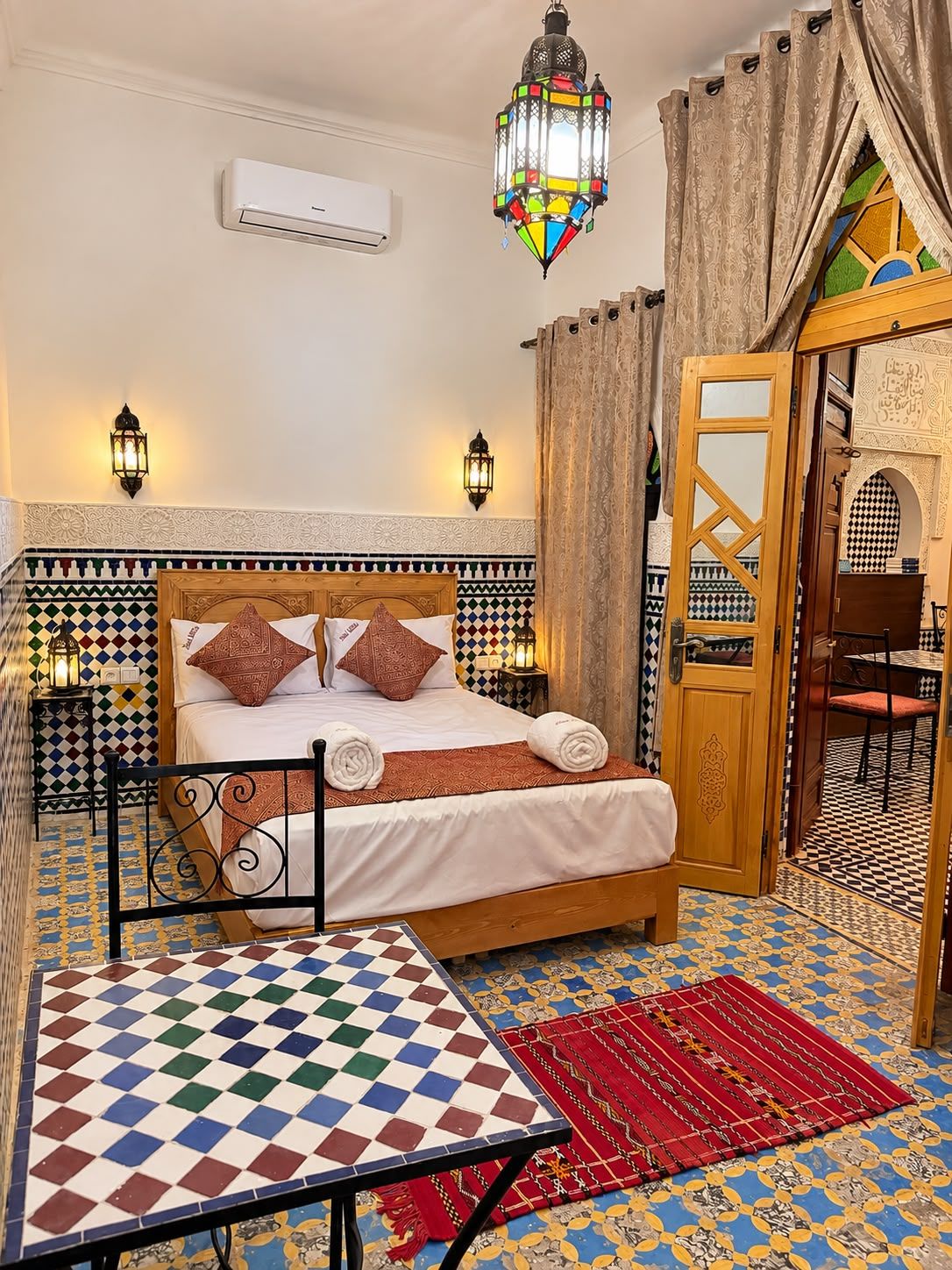 A room with a bed, a table, and a patterned floor.