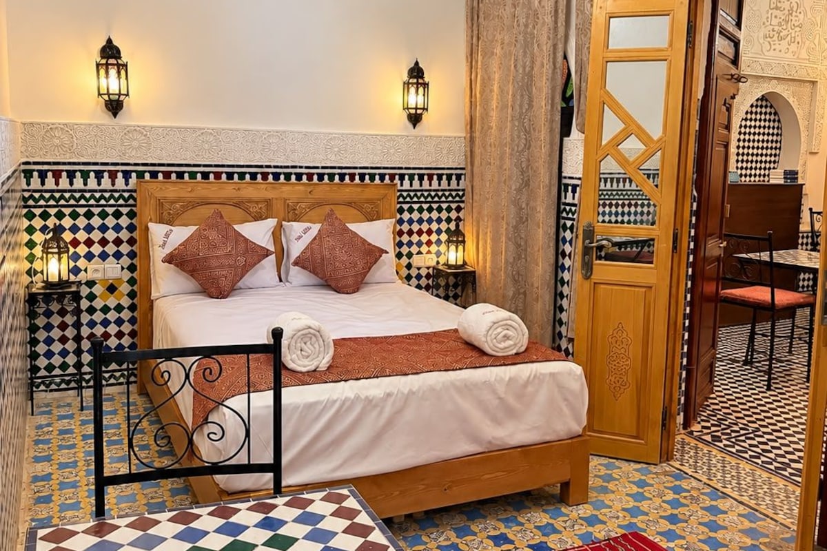 A room with a bed, a table, and a patterned floor.