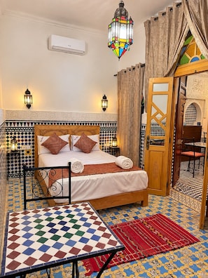 Una habitación con cama, una mesa y piso con diseño.