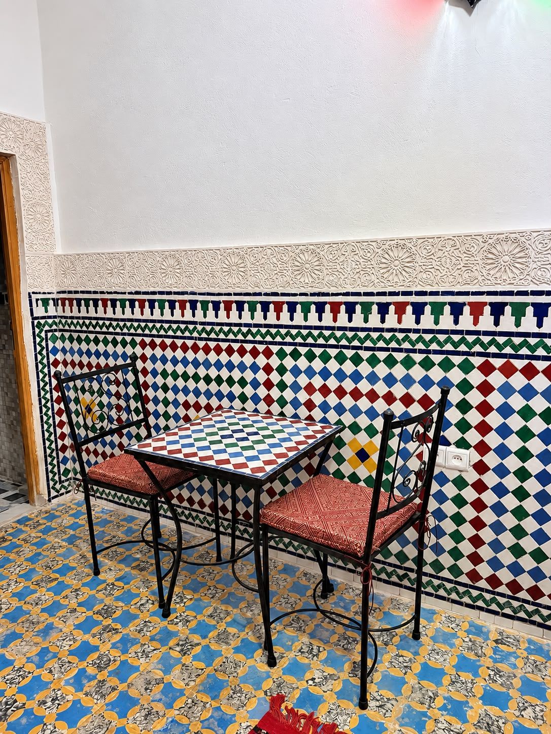Um quarto com piso estampado, uma mesa e cadeiras, e uma parede decorativa.
