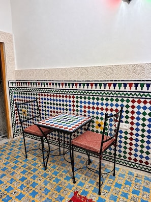 A room with a patterned floor, a table with chairs, and a decorative wall.