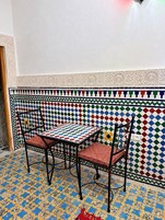 Um quarto com piso estampado, uma mesa e cadeiras, e uma parede decorativa.