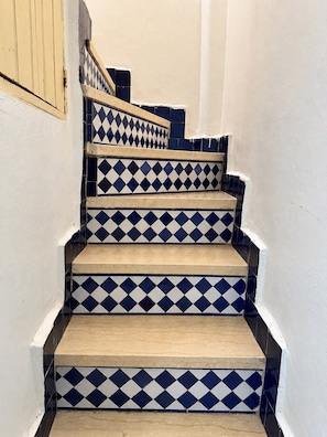 A staircase with alternating blue and white diamond-patterned tiles and wooden steps. - Riad Nasma Fes (Fes)