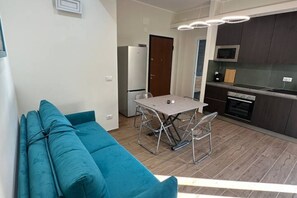 Moderni keittiö, jossa on ruokapöytä ja -tuolit, sohva ja mikroaaltouuni.