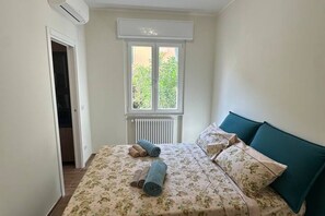 Makuuhuone, jossa on sänky, tyynyjä, ikkuna ja ilmastointilaite.