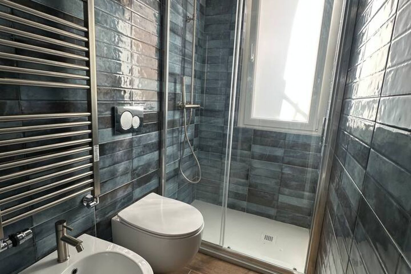 A modern bathroom with a glass-enclosed shower, a toilet, and a sink.