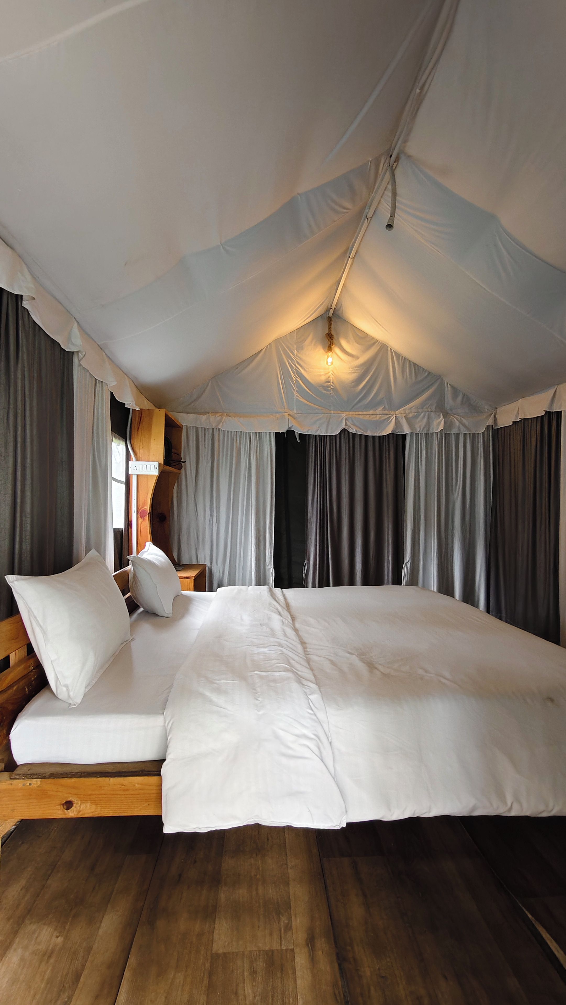 A tented room with a large bed, wooden headboard, and curtains.