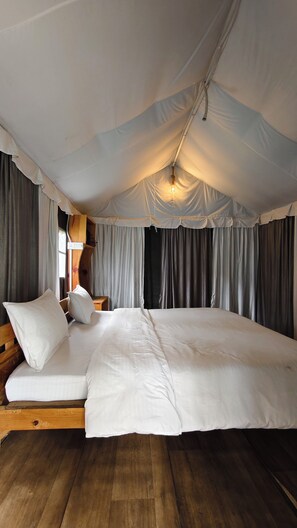 Quarto com tenda, cama grande, cabeceira de madeira e cortinas.
