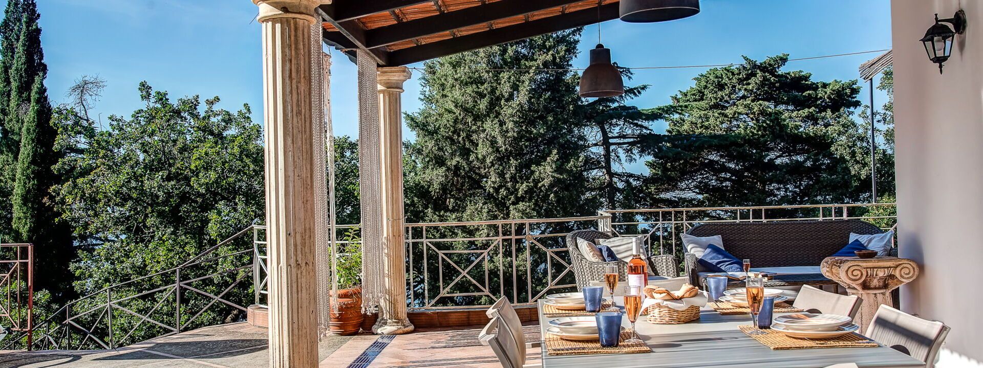 Un espace extérieur aménagé pour les repas, avec une pergola, des meubles en osier et une table dressée pour un repas.
