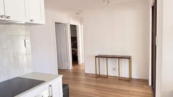 A modern kitchen with a built-in oven and stovetop, wooden flooring, and a small table with a power outlet.