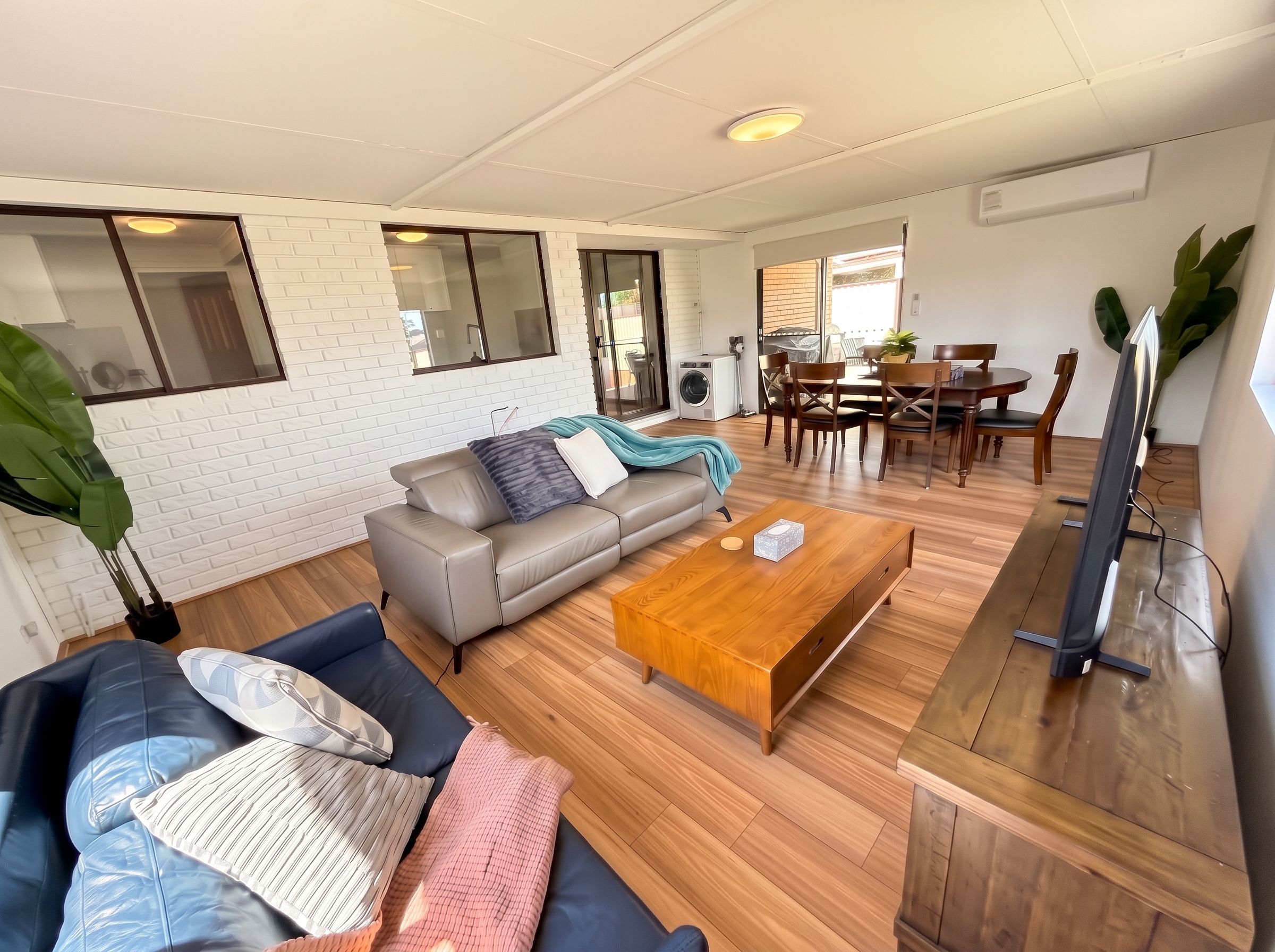 A modern living room with a sofa, coffee table, and dining area.