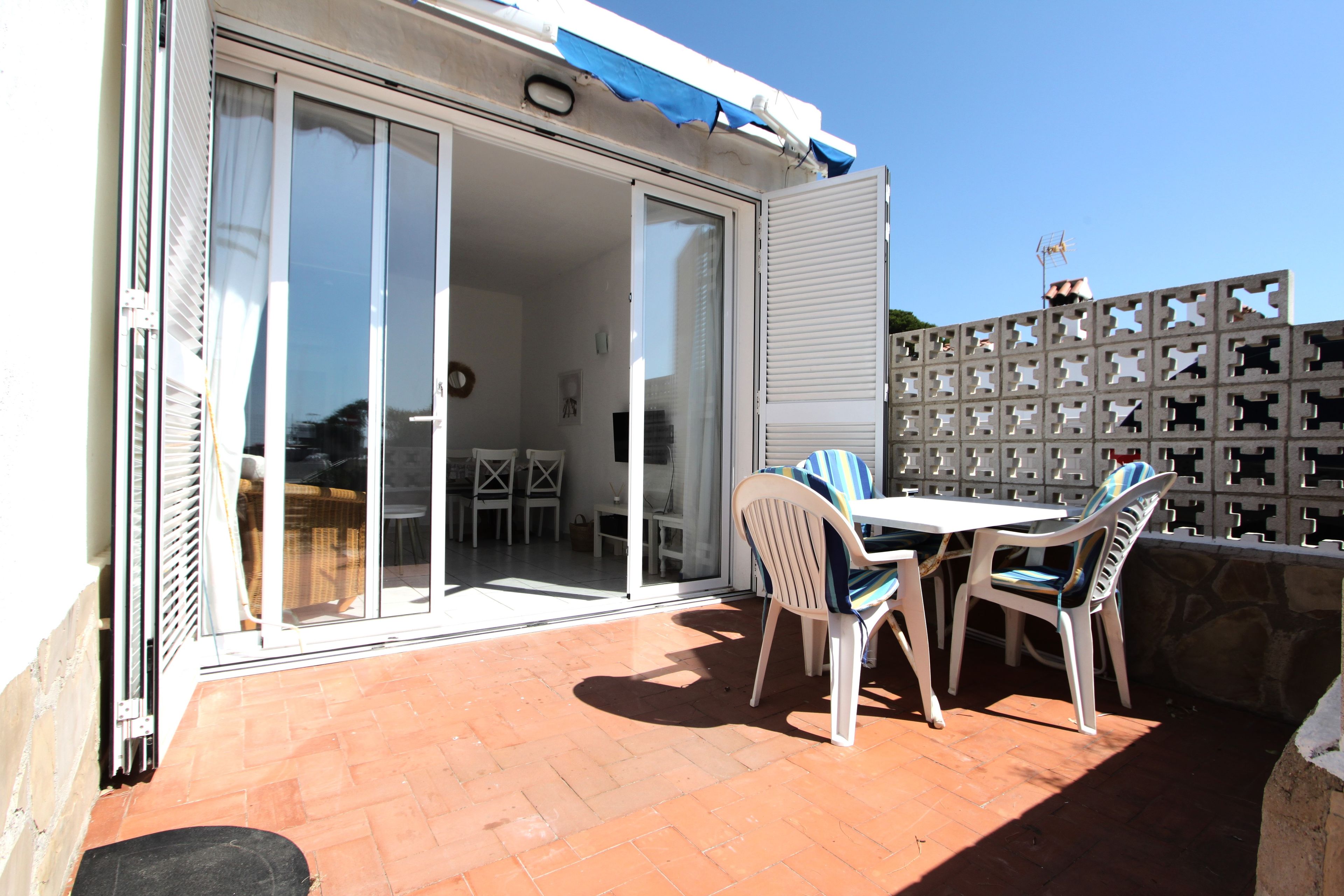 A patio with a table and chairs, a sliding glass door leading to an interior space, and a blue awning above.