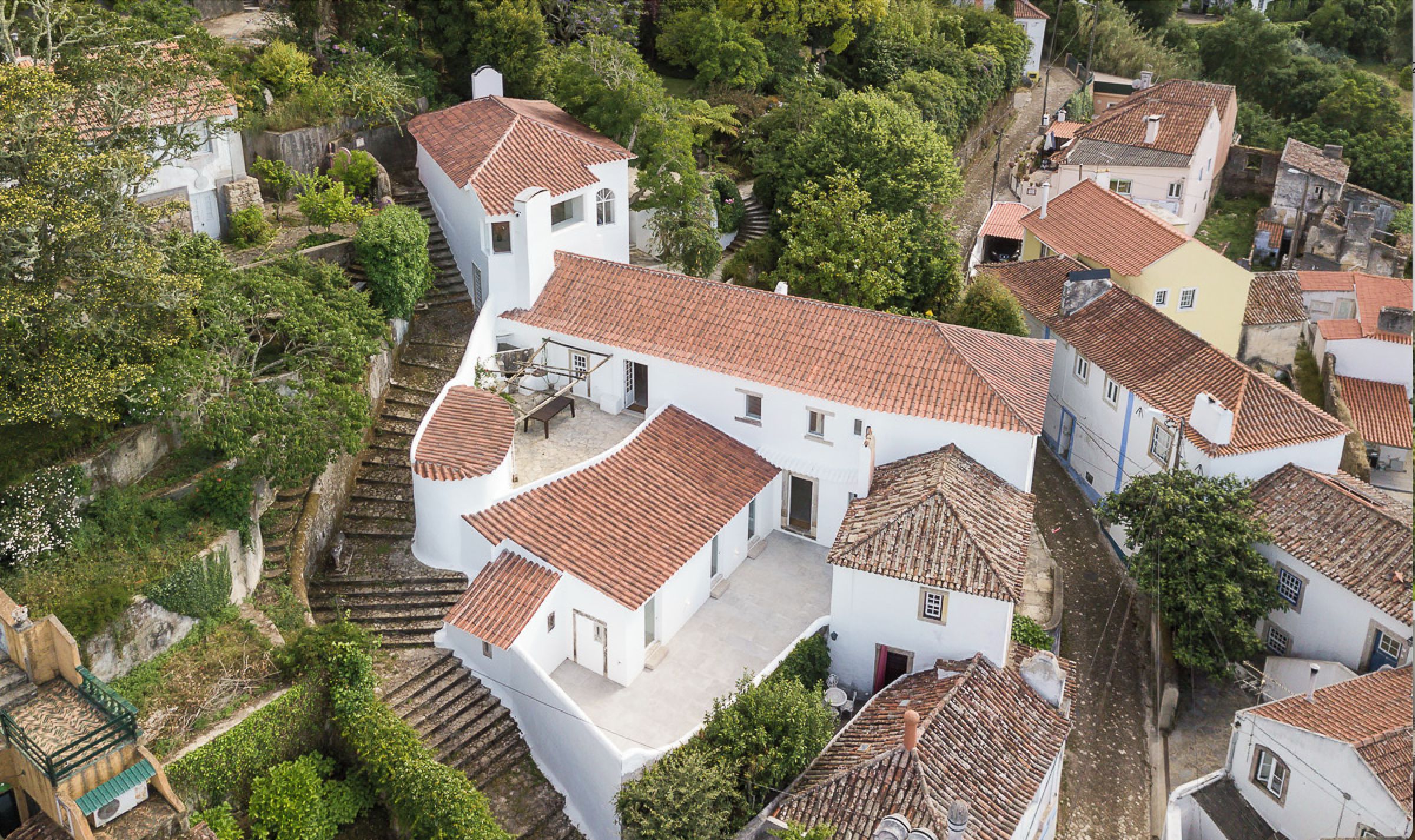 A residential area with terraced houses, steep staircases, and lush greenery.