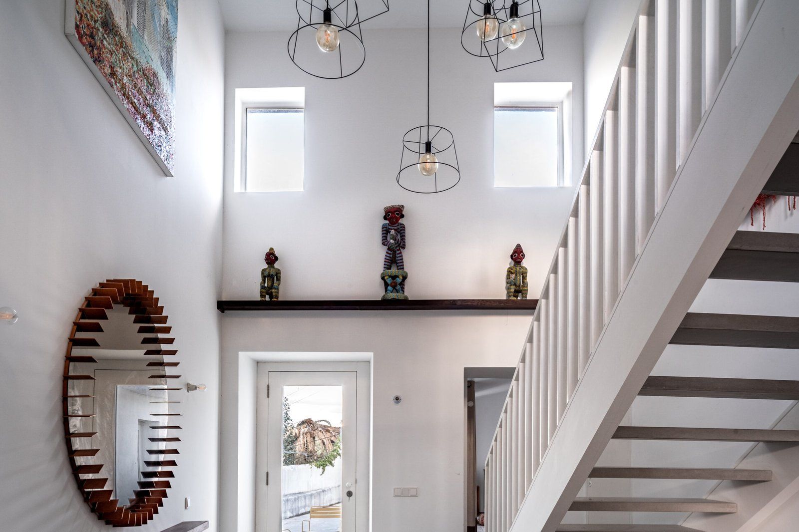 Un intérieur moderne avec un escalier, un grand miroir et un luminaire au plafond.