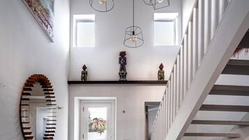 Un intérieur moderne avec un escalier, un grand miroir et un luminaire au plafond.