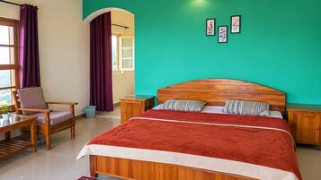 A bedroom with a wooden bed, a chair, a small table, a window with curtains, and a green wall.
