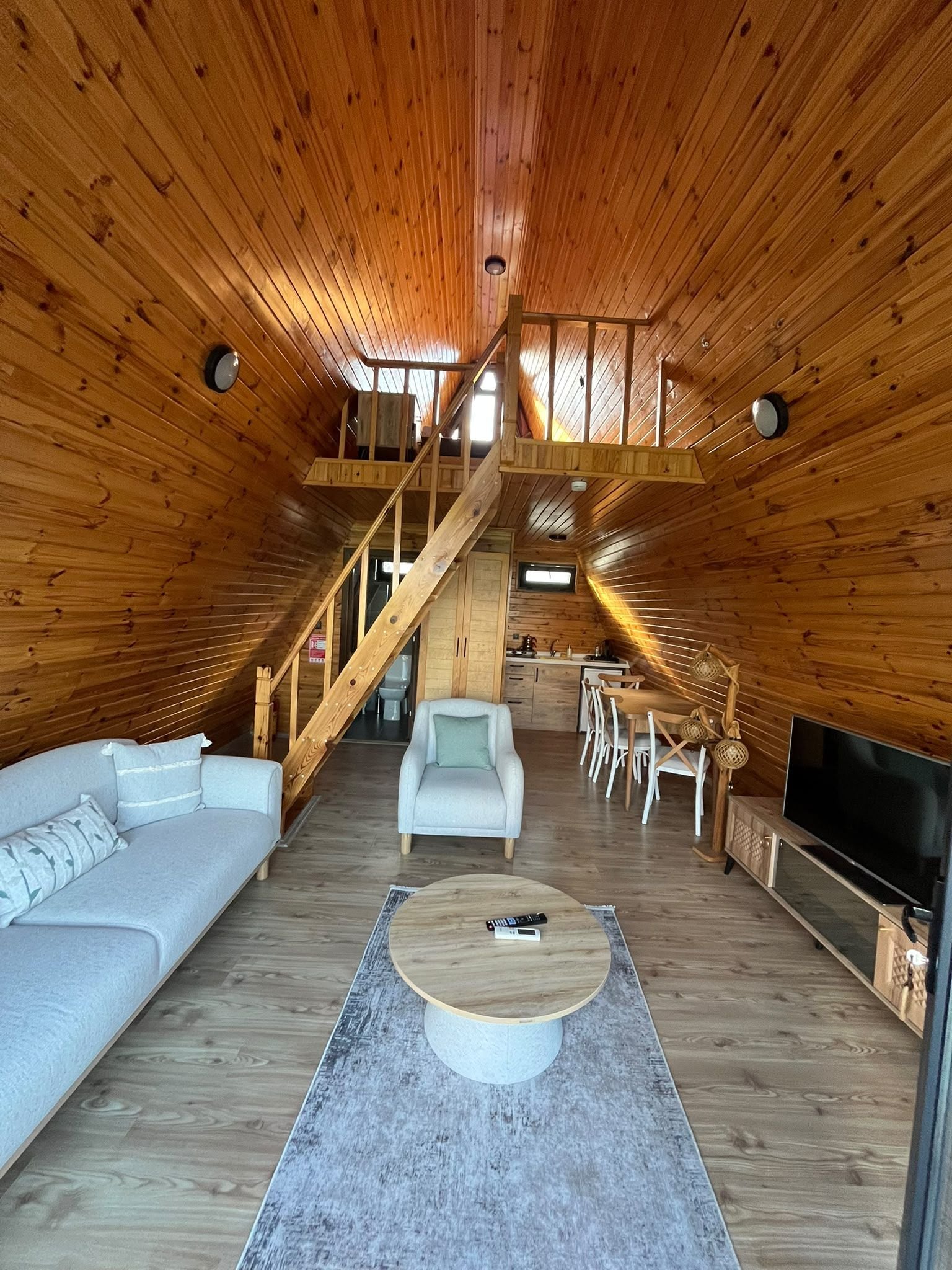 Amplio espacio tipo loft con interior de madera, un sofá, una mesa de centro y un televisor.