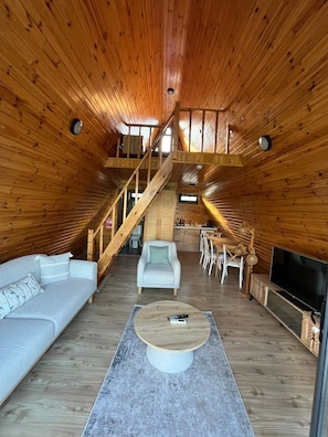 Ett rymligt rum i loftstil med träinredning, en soffa, ett soffbord och en tv.
