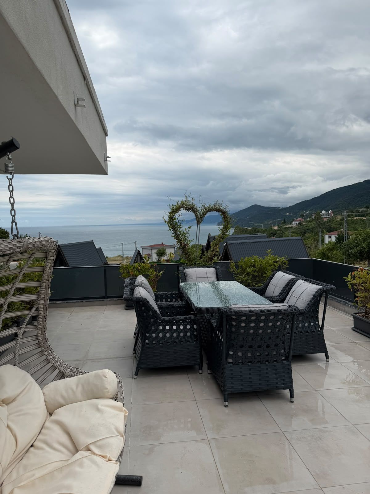 An outdoor patio with wicker furniture and a heart-shaped plant arch.