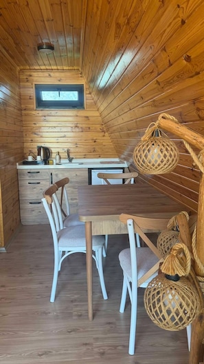 En ombonad träinredning med ett matbord, stolar, ett köksområde och ett takfönster.