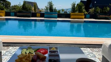 Una bandeja con comida y una taza de café junto a una piscina.