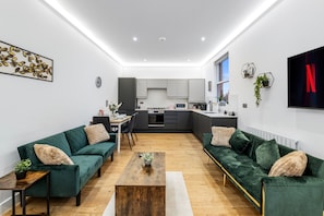 A modern living room with a sofa set, a coffee table, and a dining area with chairs. - Apartment Sleeps 7 With Wifi (London)