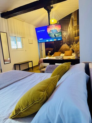 A hotel room with a bed, a desk, a television displaying a game, and a mural on the wall. - "A Magical Getaway with TV 360º" Loft Alegría in Jerez (Jerez de la Frontera)