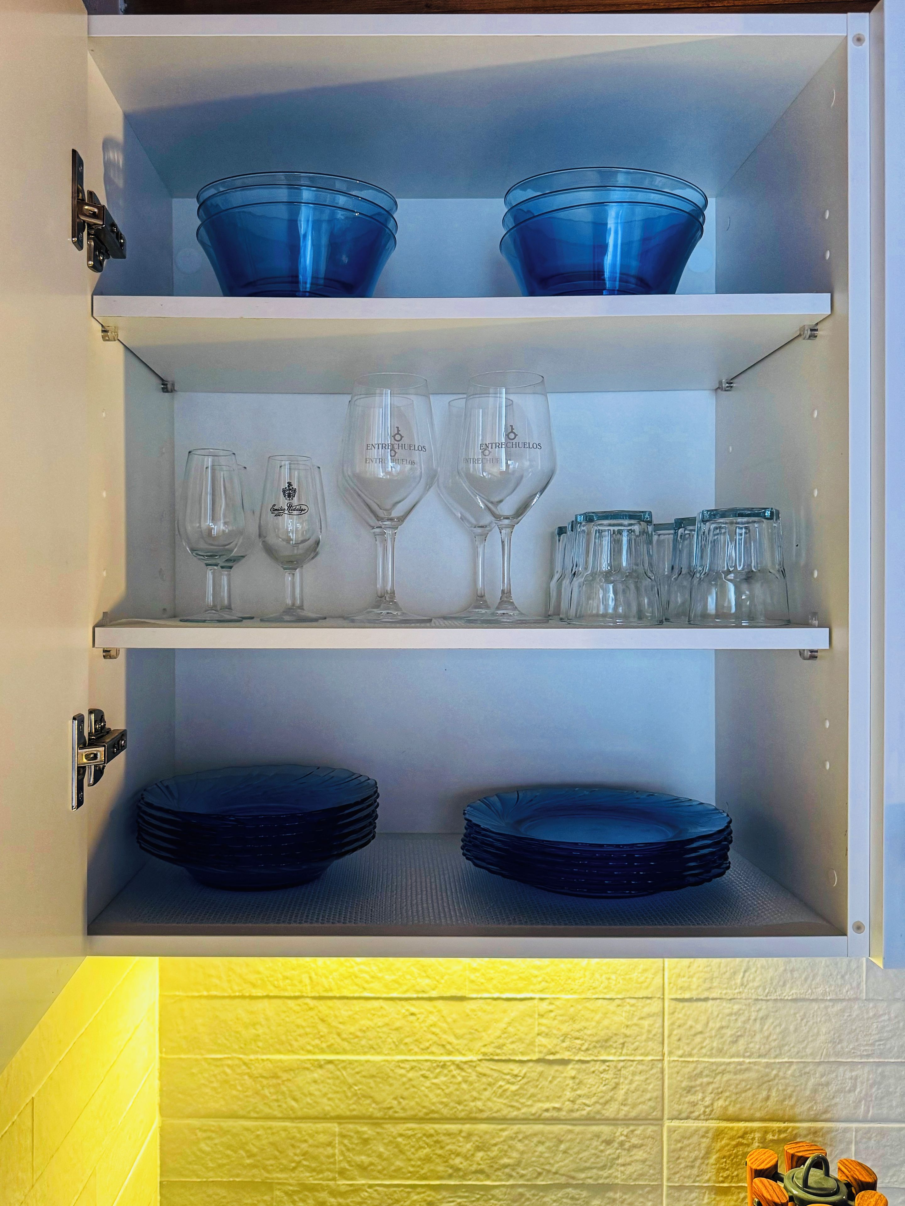 Un armario de almacenamiento con estantes que contienen copas de vino, cuencos y platos.