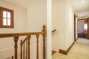 A staircase with wooden balusters and a handrail, leading to a room with a bed and a window. - Hotel Tótem de Mar (Valeria del Mar)