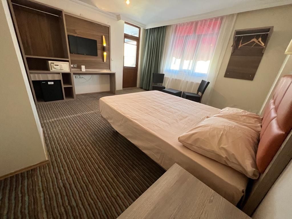Una habitación de hotel con cama, escritorio, televisor y armario.