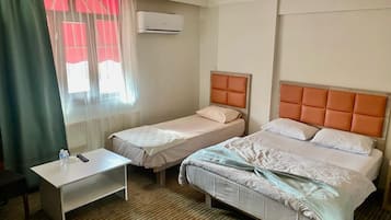 Habitació d'hotel amb dos llits, una taula petita i una finestra amb cortines.