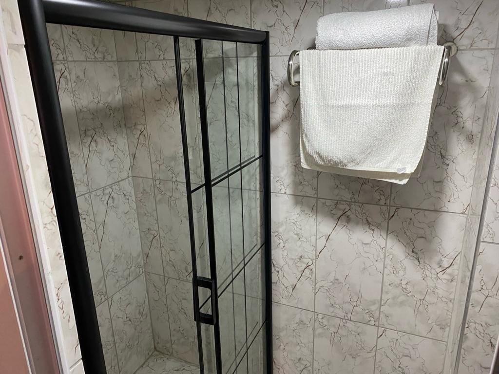 Un baño con cabina de ducha y toallero con una toalla blanca.