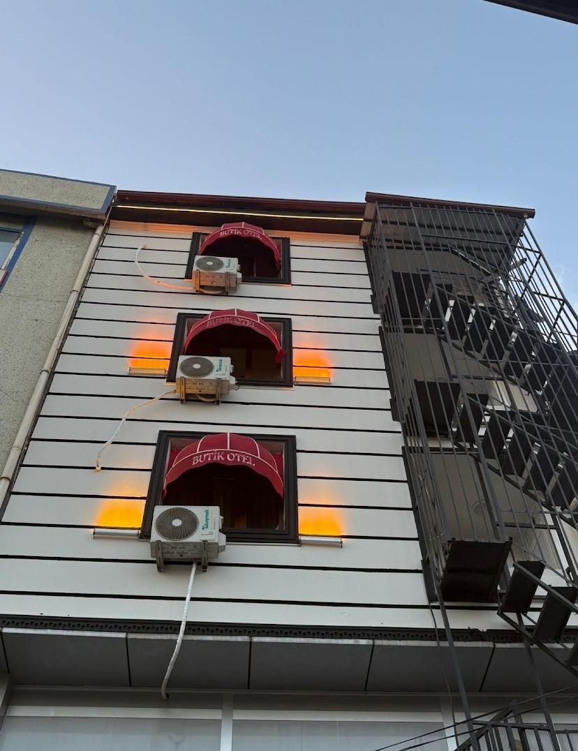 A building with three windows, each with a red awning and an air conditioning unit.