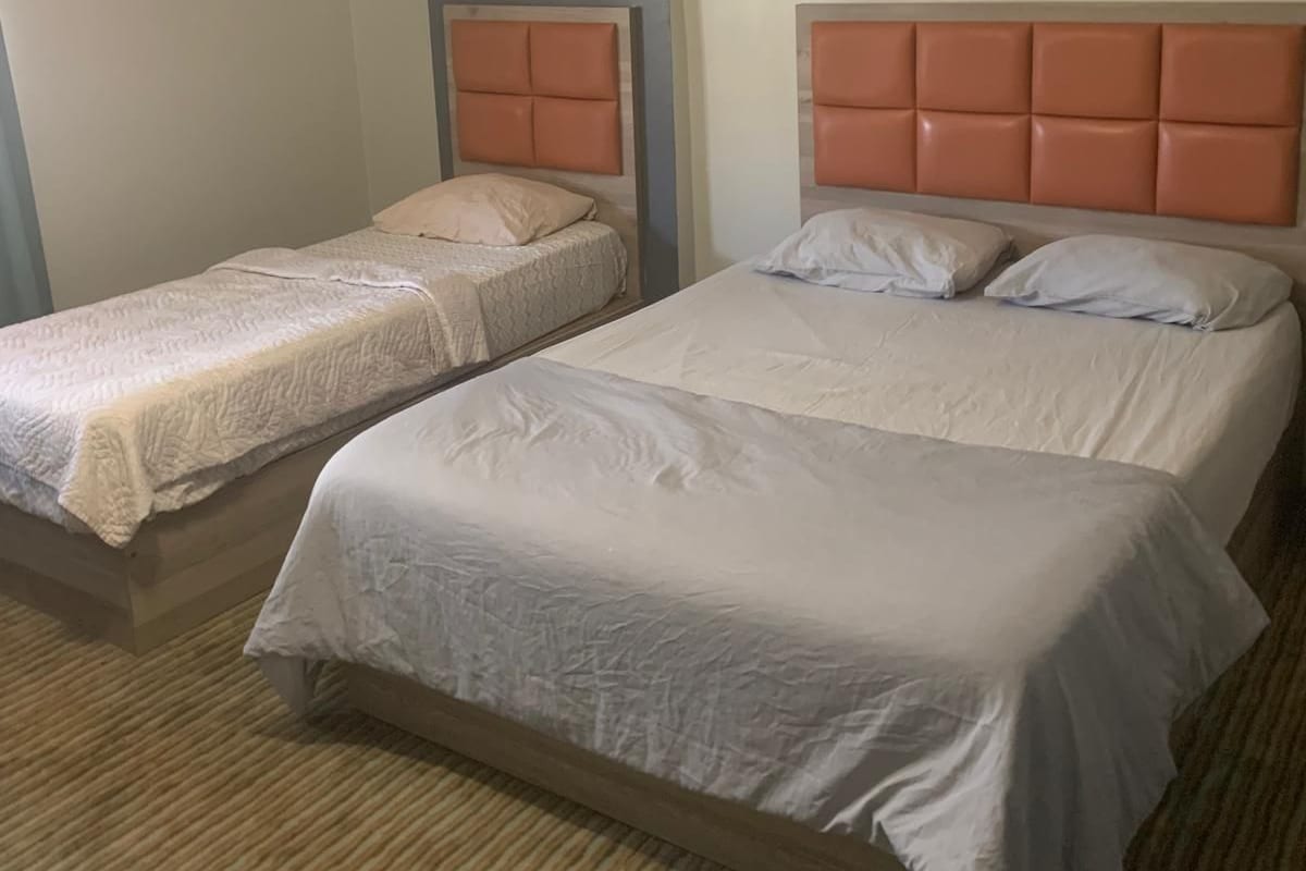 Una habitación de hotel con dos camas individuales, aire acondicionado de pared y una lámpara en el techo.