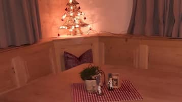Interior de fusta amb taula de menjador, seient i lluminària decorativa.