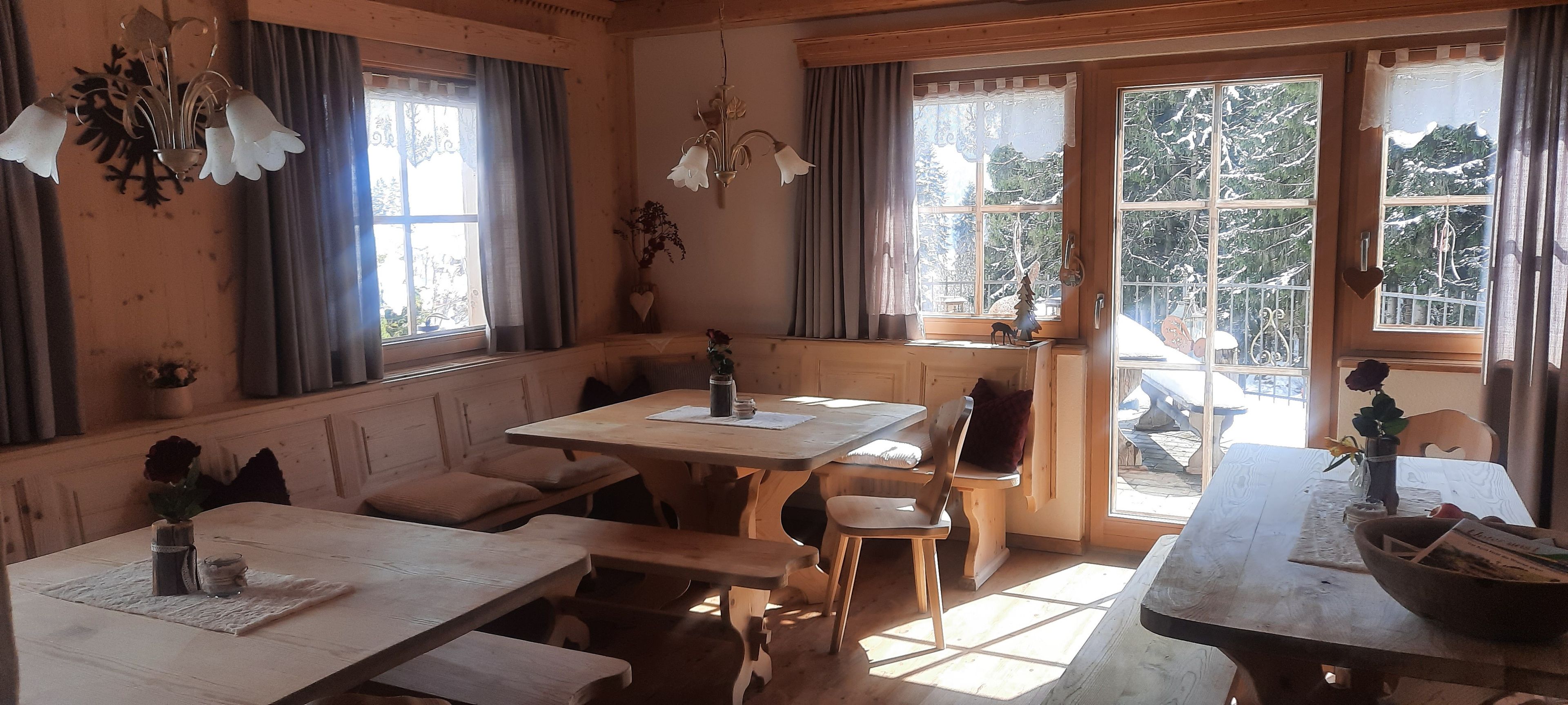 A cozy room with wooden furniture, large windows, and a view of a snowy landscape.